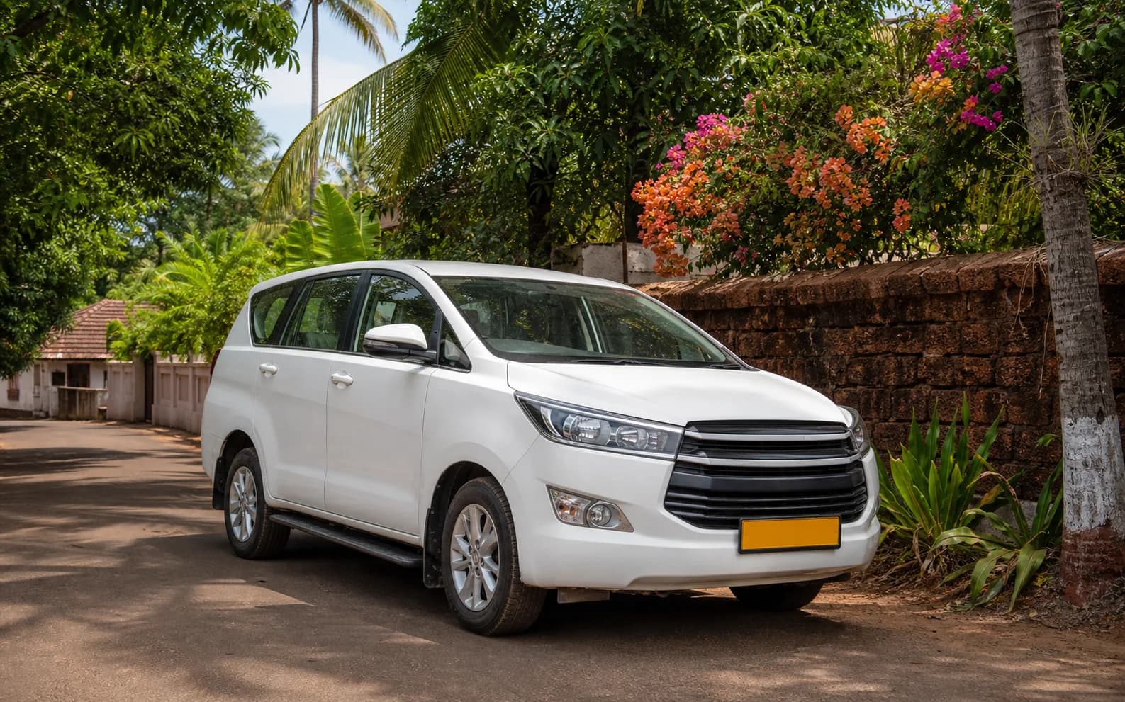 A white seven-seat Goa taxi on a shaded village road