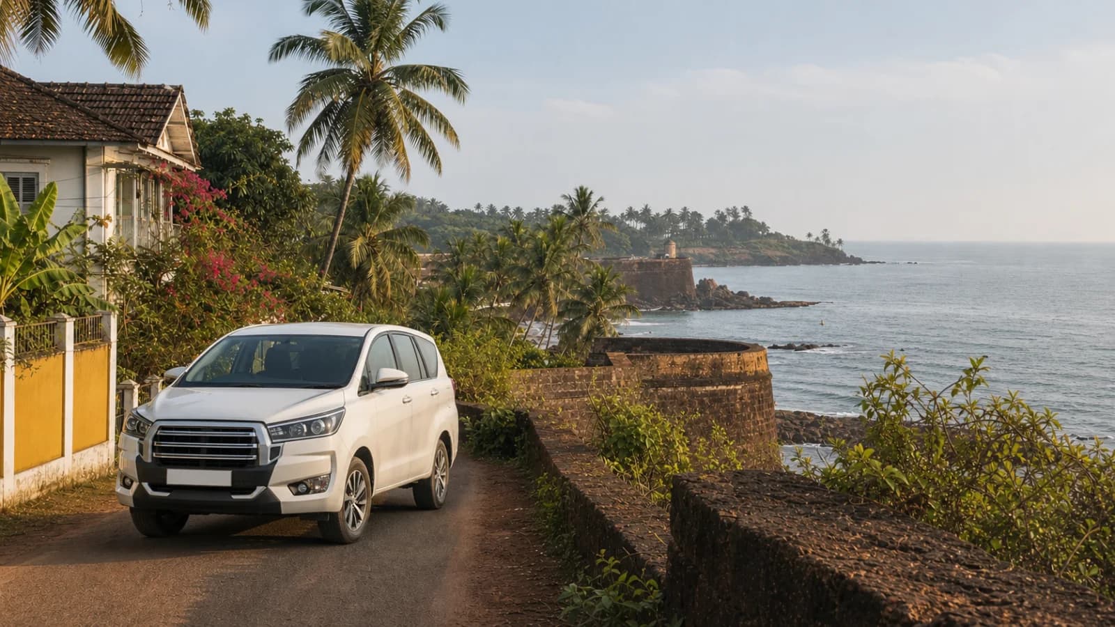 White Innova Crysta class vehicle on a coastal road in North Goa