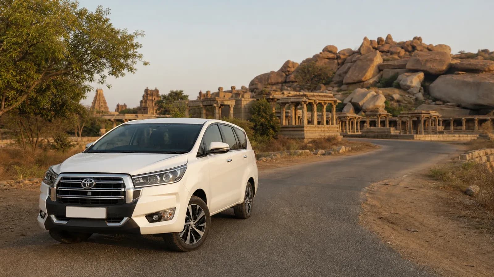 White Innova Crysta class vehicle on the approach road to Hampi