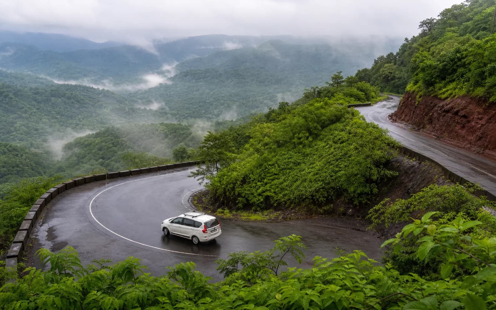 A private cab rounding a green Western Ghats road after rain